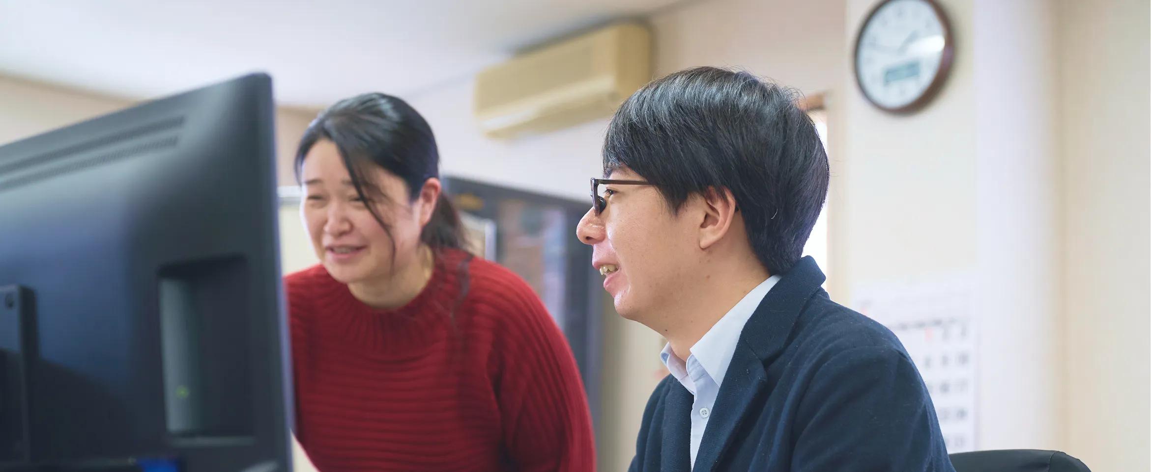 先輩に指導を受けながら楽しそうに仕事をする小根山の画像